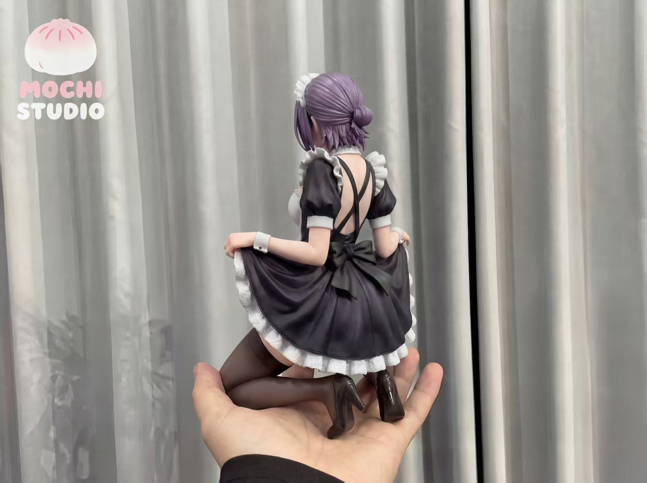 Maid Reze resin statue rear view showing open back and oversized bow, held in hand for scale